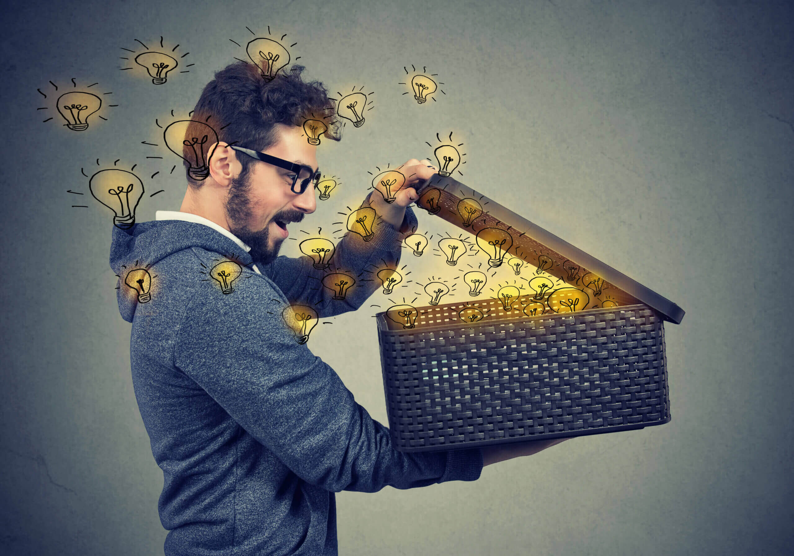 Happy surprised man opening a box with many bright light bulbs flying out